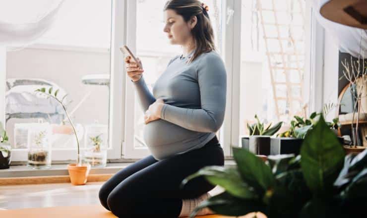pregnant woman squarting holding a phone